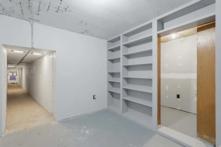 Built-in shelving unit with multiple tiers, opens to a hidden "safe room" with a long built-in gun range.