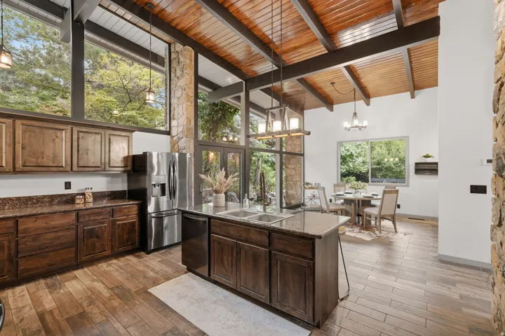 Open-concept kitchen and dining area featuring a vaulted wood-paneled ceiling with exposed beams