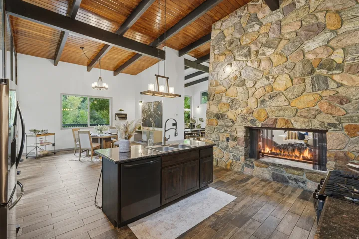 Spacious open-concept living area featuring a stone fireplace, granite countertops and included appliances