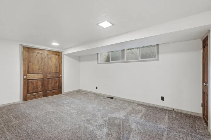 Carpeted room featuring a double wood-paneled closet, light walls, and recessed lighting