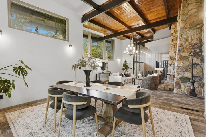 Spacious dining area featuring a prominent stone fireplace, and an exposed wood beam ceiling