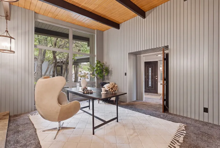 Interior space featuring vertical paneled walls and exposed wood beam ceiling