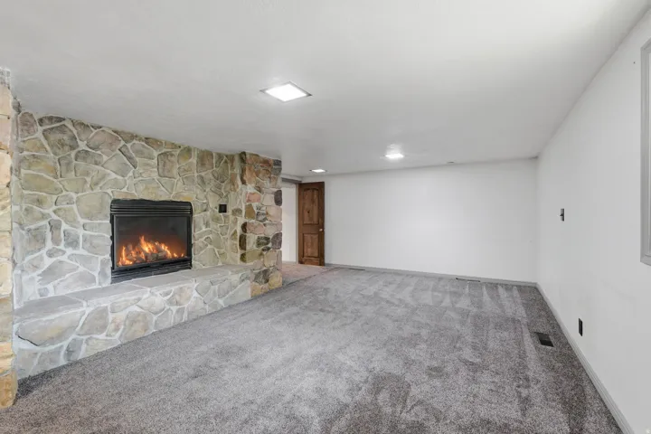 Expansive room featuring a stone-clad fireplace with a raised hearth