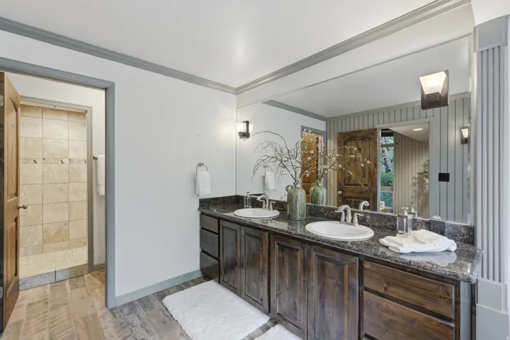Dual vanity with dark wood-finish cabinetry and stone countertops