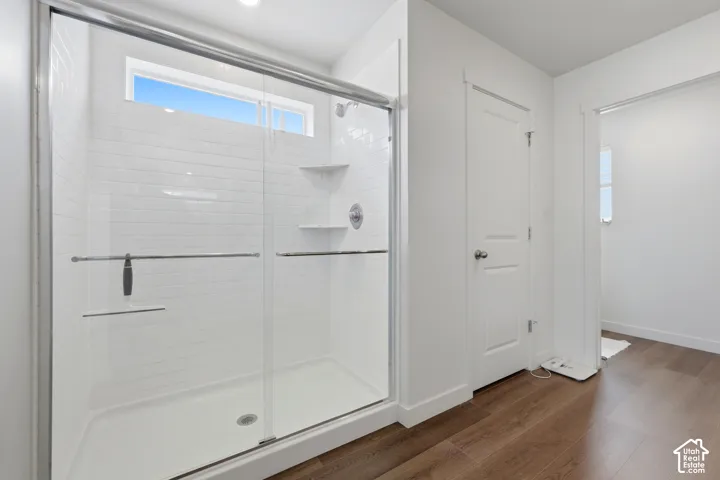 Spacious shower enclosure featuring subway tile surround, built-in shelving, chrome fixtures, and a transom window