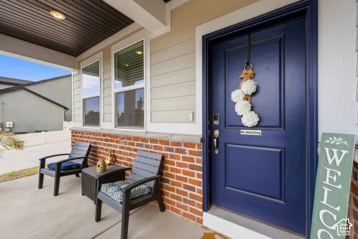Inviting front porch featuring a dark blue entry door, brick wainscoting, light-colored siding, and a soffit ceiling with recessed lighting