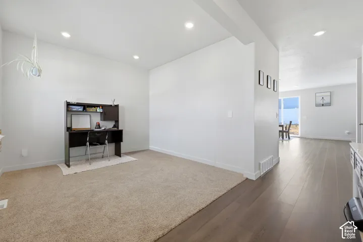 Bright interior space featuring recessed lighting, a neutral color palette, and a combination of carpet and wood-finish flooring