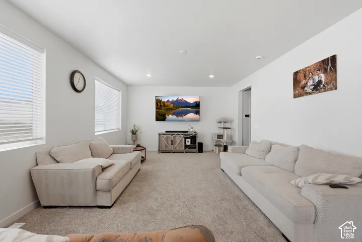 Spacious living area featuring light gray walls, recessed lighting, and soft carpet flooring