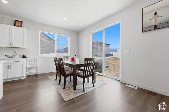Open concept dining area featuring wood-finish flooring, white cabinetry, a large sliding glass door, and recessed lighting