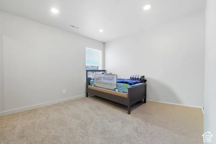 Carpeted room featuring a single window with blinds, recessed lighting, and light-toned walls