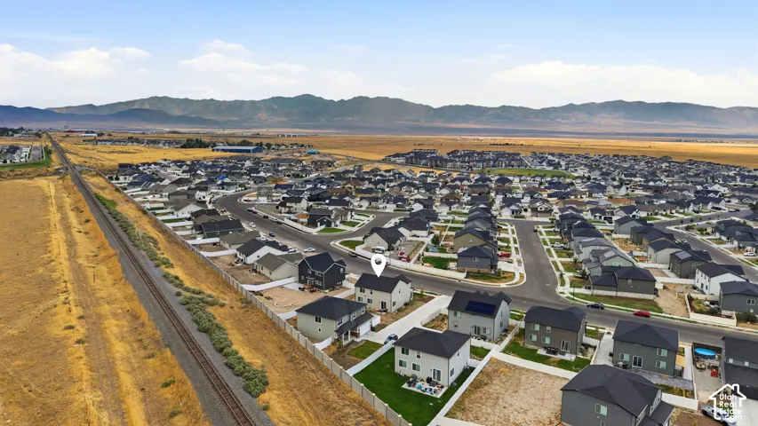 Expansive residential community with various home styles under construction, featuring organized street layouts and mountain backdrops