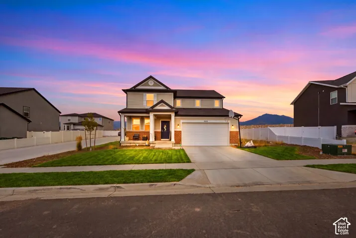 Two-story residence featuring a covered front porch, an attached two-car garage, and a manicured front lawn