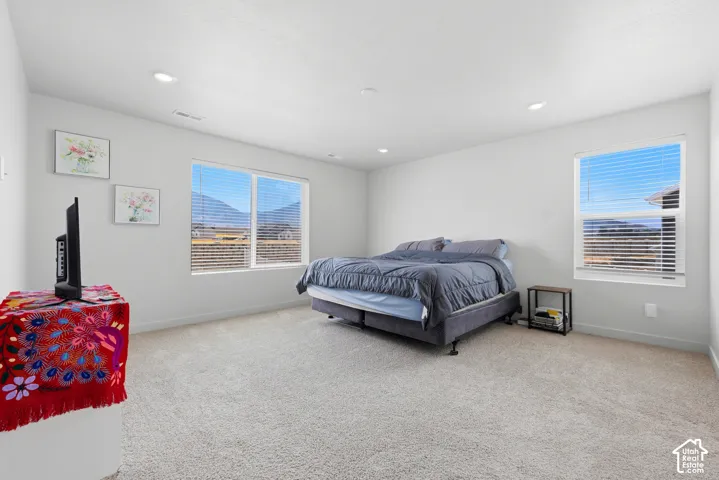 Spacious room featuring neutral carpeting, recessed lighting, and multiple windows with horizontal blinds