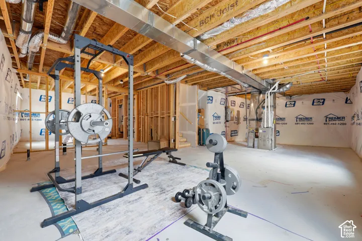 Unfinished basement featuring exposed wood framing, concrete flooring, and visible HVAC ductwork