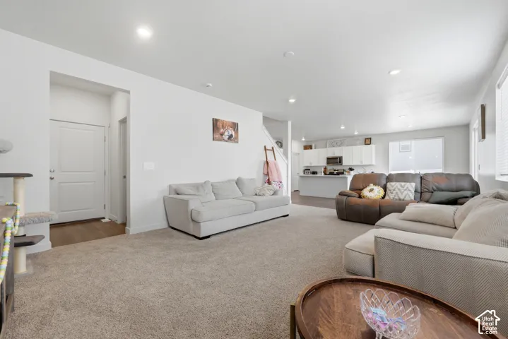Spacious living area featuring neutral carpeting, recessed lighting, and ample natural light from multiple windows