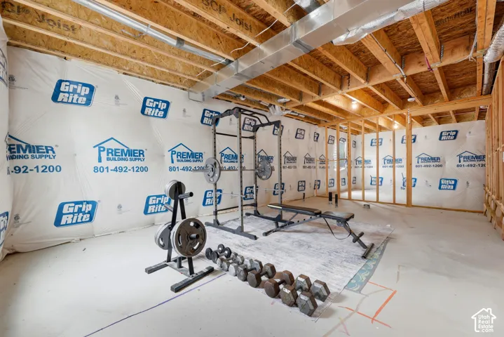 Unfinished basement with exposed ceiling joists and ductwork, featuring framed walls and a concrete floor