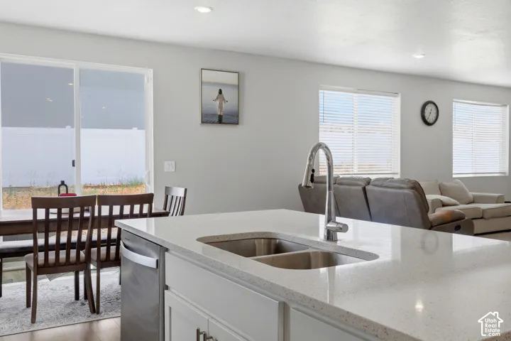 Kitchen island featuring a dual basin undermount stainless steel sink, gooseneck faucet, and light-toned solid surface countertop