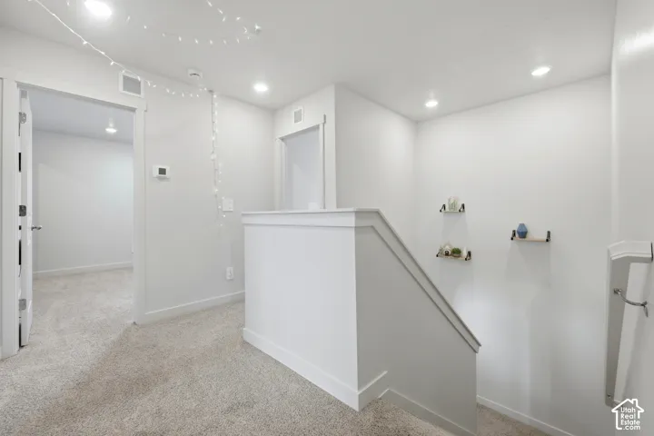 Upper landing with neutral carpeting, recessed lighting, white trim, and doors leading to other rooms