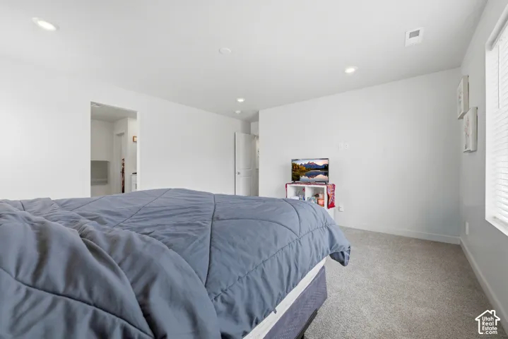 Carpeted bedroom with recessed lighting and neutral wall finishes