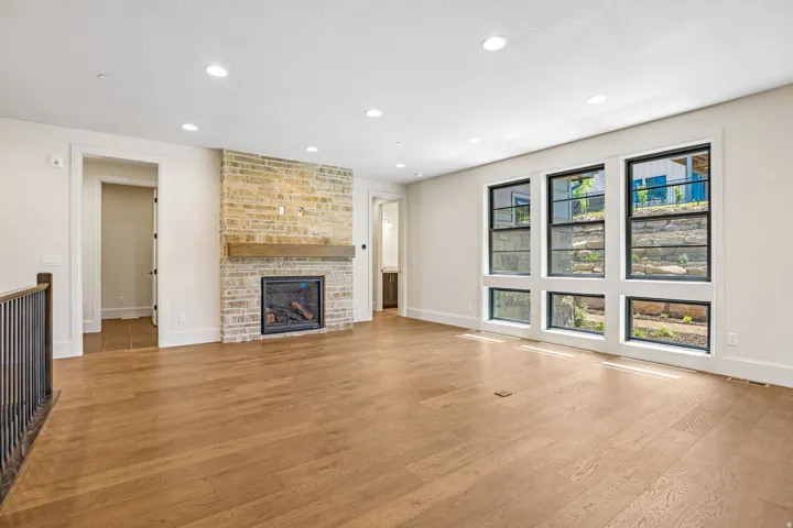 Living area featuring a brick fireplace with a wood-finish mantel, recessed lighting, and light wood-finish flooring