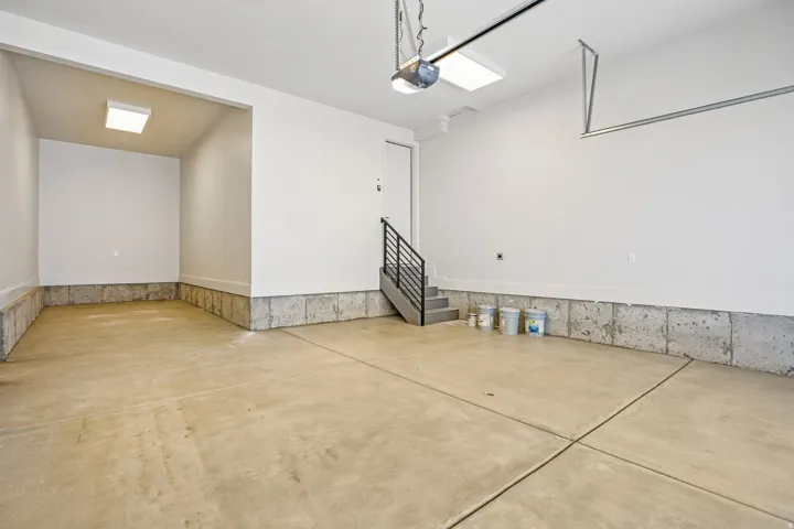 Spacious garage with concrete flooring, bright overhead lighting, and an integrated storage alcove