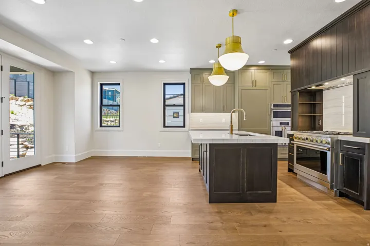 Spacious kitchen and living area featuring wood-finish flooring, recessed lighting, and a white color palette
