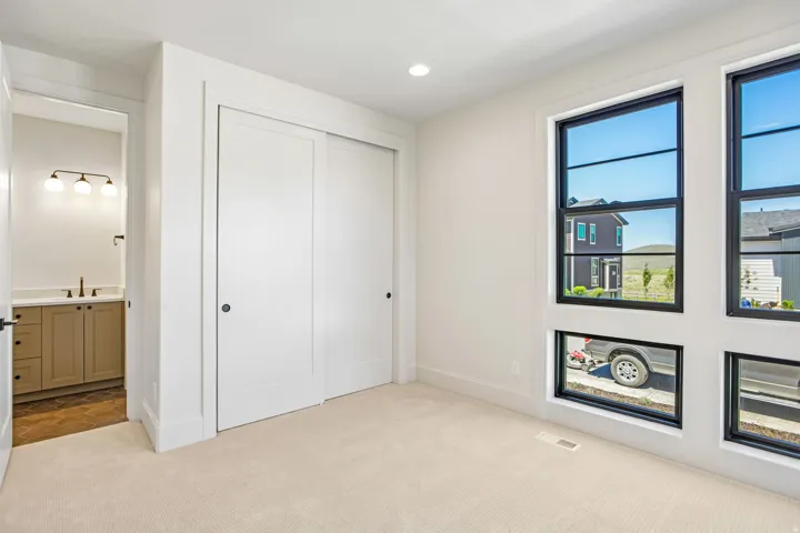 Bright room featuring large black-framed windows, plush carpet flooring, recessed lighting, and a double-door closet