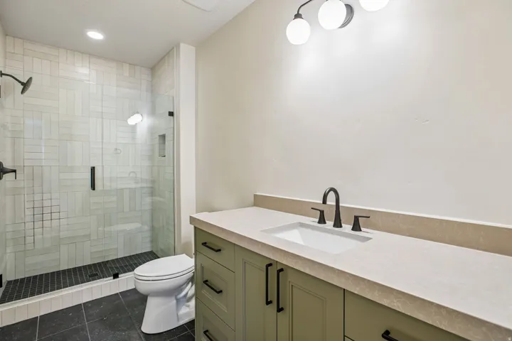 Bathroom featuring a sage green vanity with a light-toned countertop, an undermount sink, and matte black fixtures