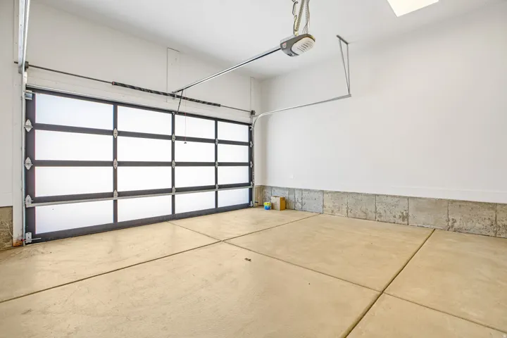 Single-car garage featuring a contemporary paneled door with translucent inserts, an automatic opener, and a concrete floor