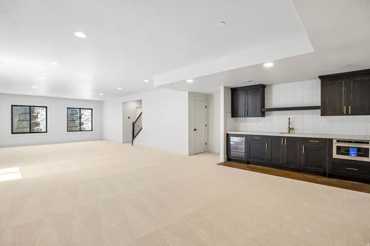 Spacious lower-level living area with recessed lighting, light-toned carpet, and two black-framed windows