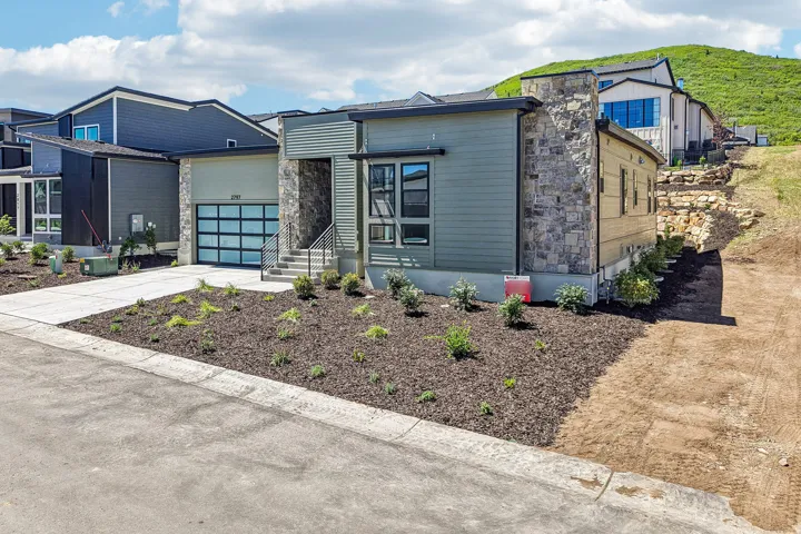 Modern exterior featuring a prominent stone facade, horizontal siding, and a contemporary glass-paneled garage door