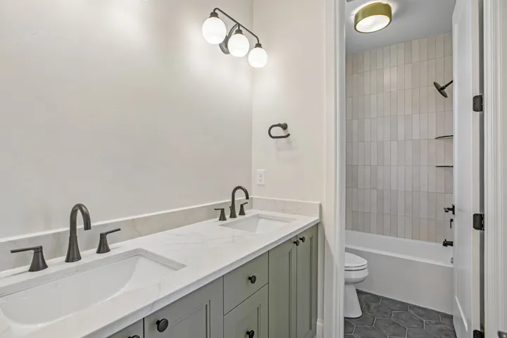 Dual vanity with integrated sinks, white countertop, and sage green cabinetry