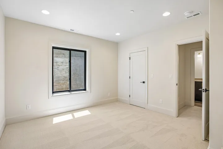 Neutral-toned room featuring light-colored carpeting and recessed ceiling lighting