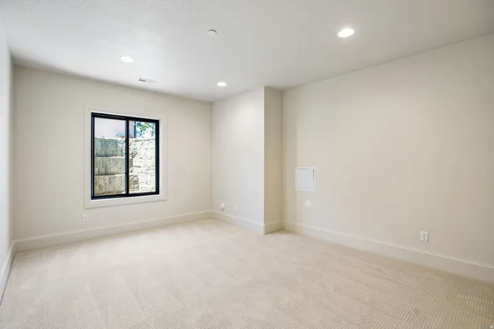 Neutral-toned room featuring light-colored carpeting, recessed lighting, and a window with a black frame