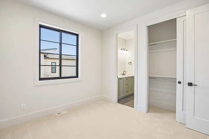 Bright room with carpet flooring, a black-framed window, and a built-in closet with double doors