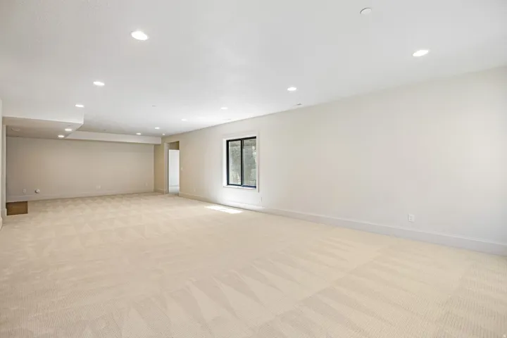Spacious room featuring light-toned carpeting and recessed ceiling lighting