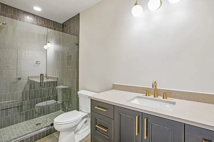 Contemporary bathroom featuring a walk-in shower with glass enclosure, vertical subway tile, and a built-in shower niche