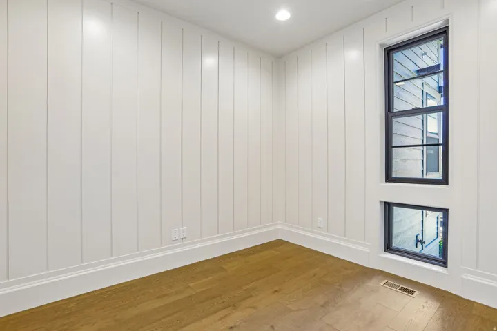Room featuring wood-finish flooring, white vertical shiplap walls, and recessed lighting