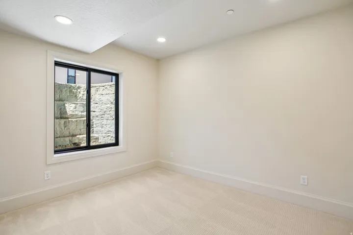 Room featuring recessed lighting, a large window with a black frame, light-colored carpeting, white baseboards, and neutral wall paint
