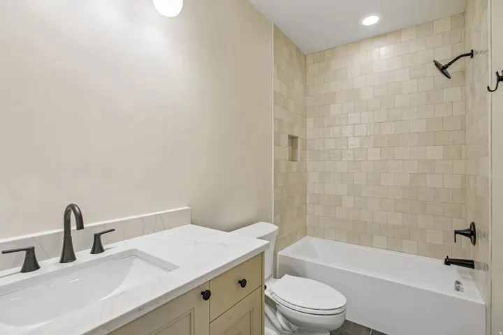 Bathroom featuring a single vanity with a white countertop, undermount sink, and matte black faucet