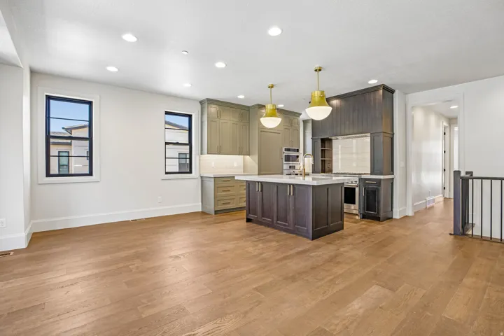 Open-concept kitchen and living area featuring wood-finish flooring, recessed lighting, and white walls