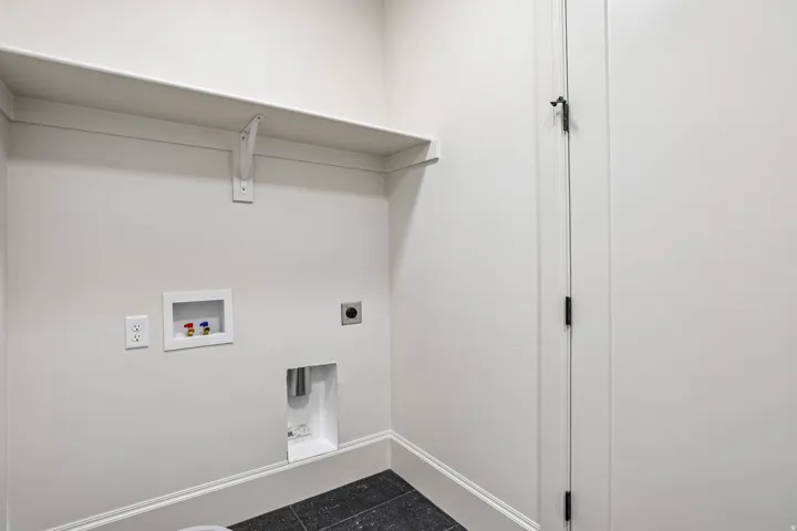 Dedicated laundry area featuring a wall-mounted shelf, electrical outlets, and plumbing hookups