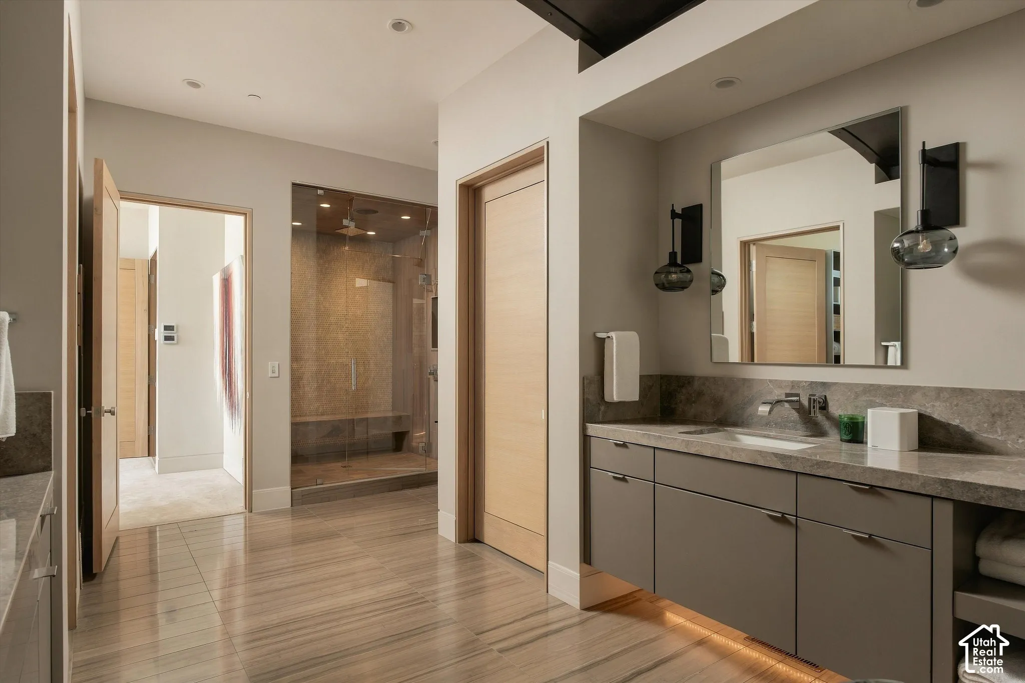 Contemporary bathroom featuring a floating vanity with integrated lighting, a spacious walk-in shower with glass enclosure and bench seating, a large vanity mirror, and modern sconce lighting