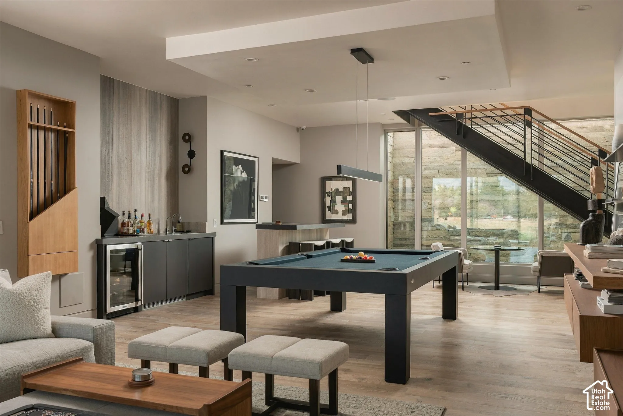 Wood-finish flooring, built-in wet bar, modern staircase with metal railings, recessed lighting, and large format windows