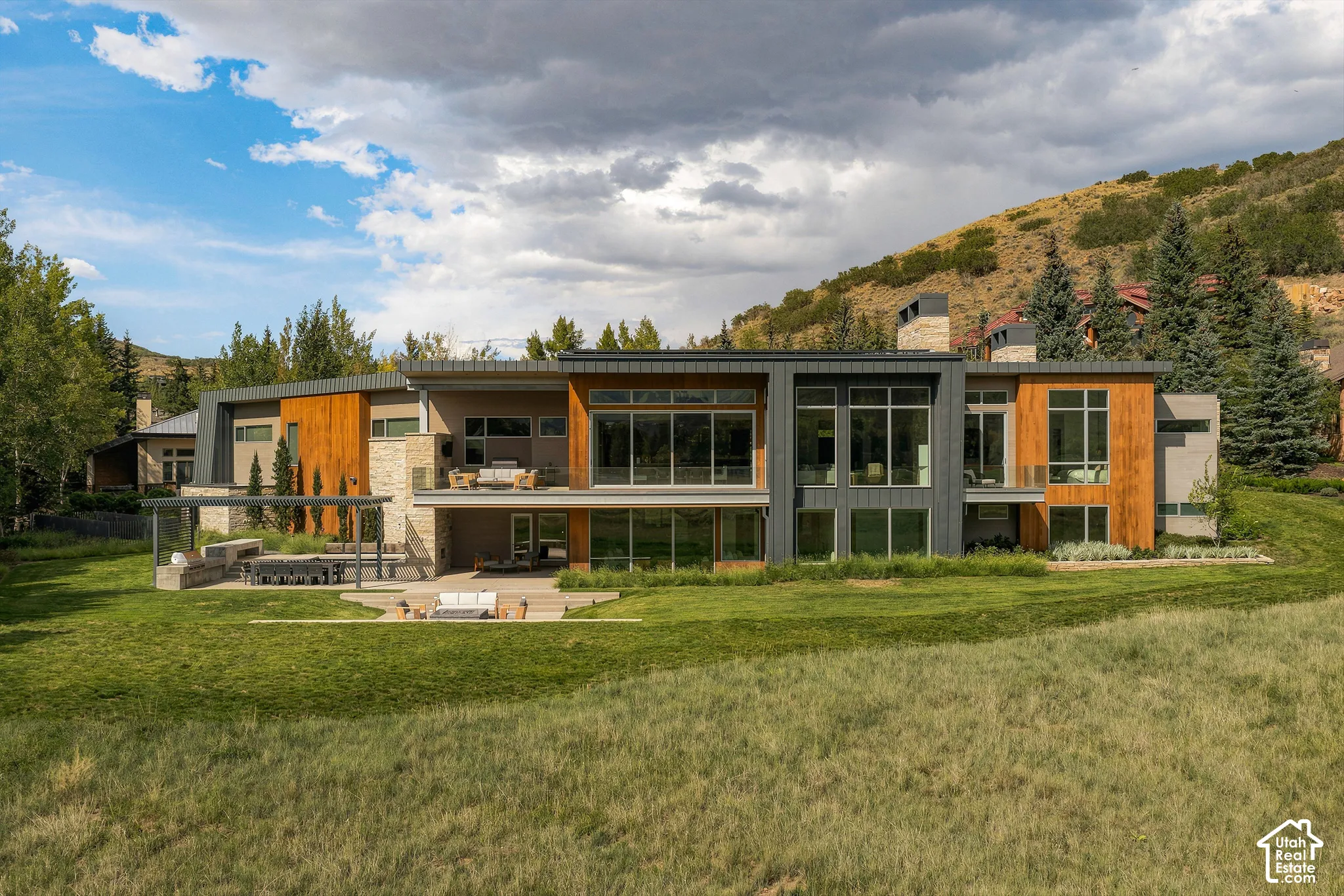 Modern multi-story exterior with expansive glass windows, wood paneling accents, and stone detailing