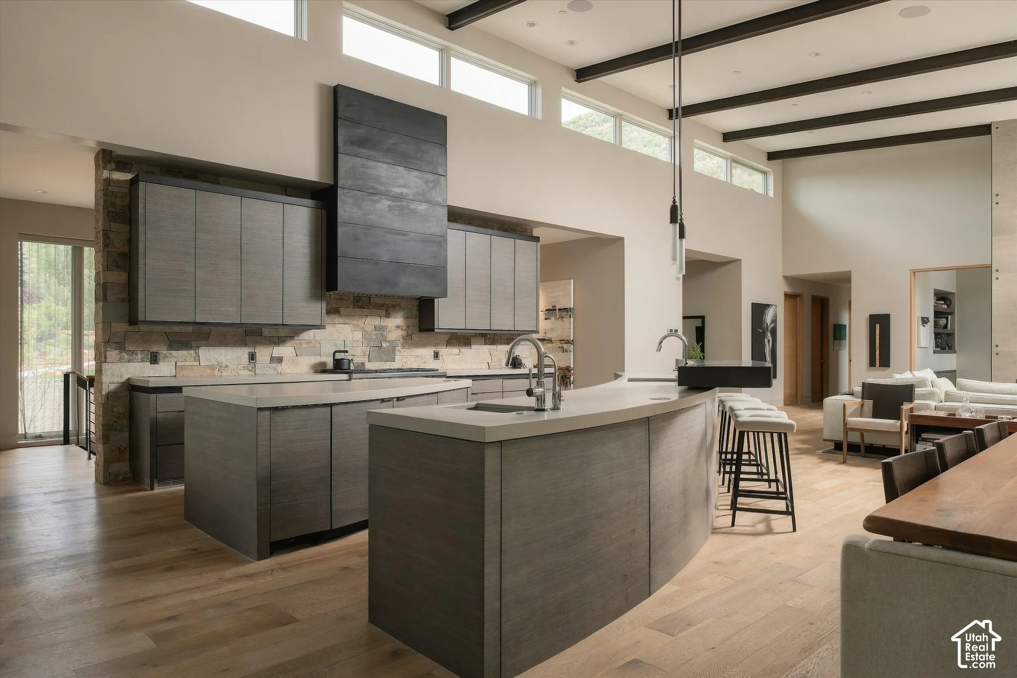 Expansive kitchen featuring dual islands, stone accent wall, wood-finish cabinetry, and high ceilings with exposed beams