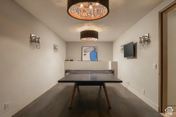 Recessed ceiling with two drum pendant light fixtures, wall-mounted sconces, and wood-finish flooring