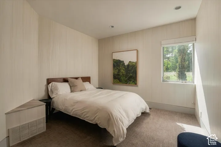 Textured wall coverings, recessed ceiling lighting, a window with a roller shade, and wall-to-wall carpeting