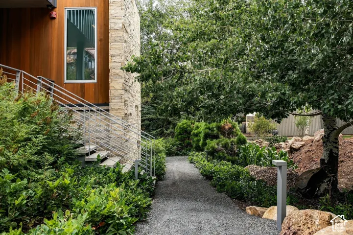 Exterior with stone cladding and wood paneling, featuring a contemporary window, metal railings, and a gravel pathway