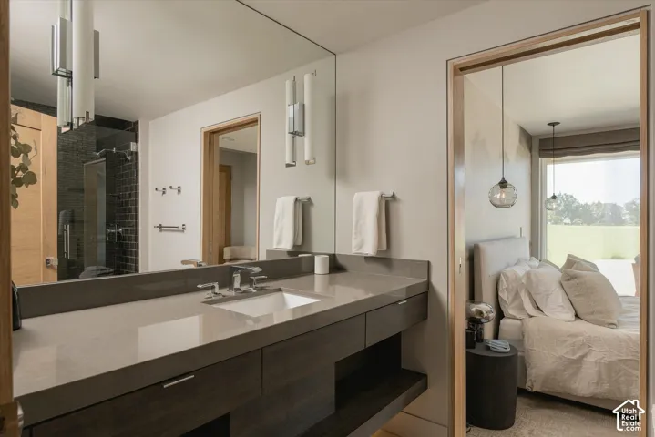 Floating vanity with integrated sink, full-width mirror, wall-mounted sconces, and a glass-enclosed shower